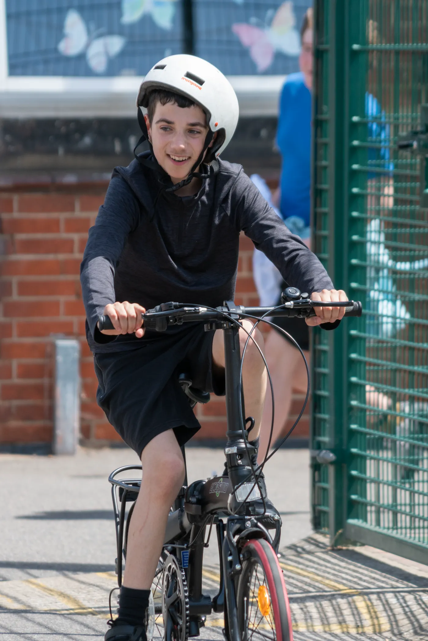 A student in a cycle helmet riding a bike across the school playground.
