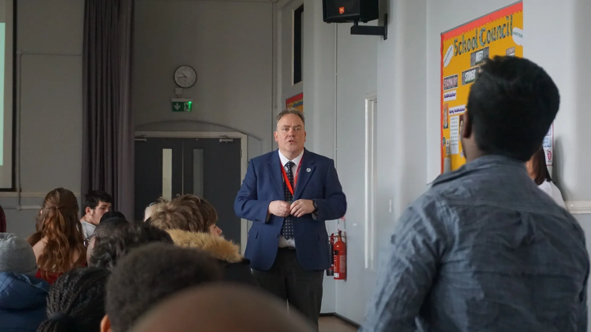 A visiting professional talking to a class of seated students.