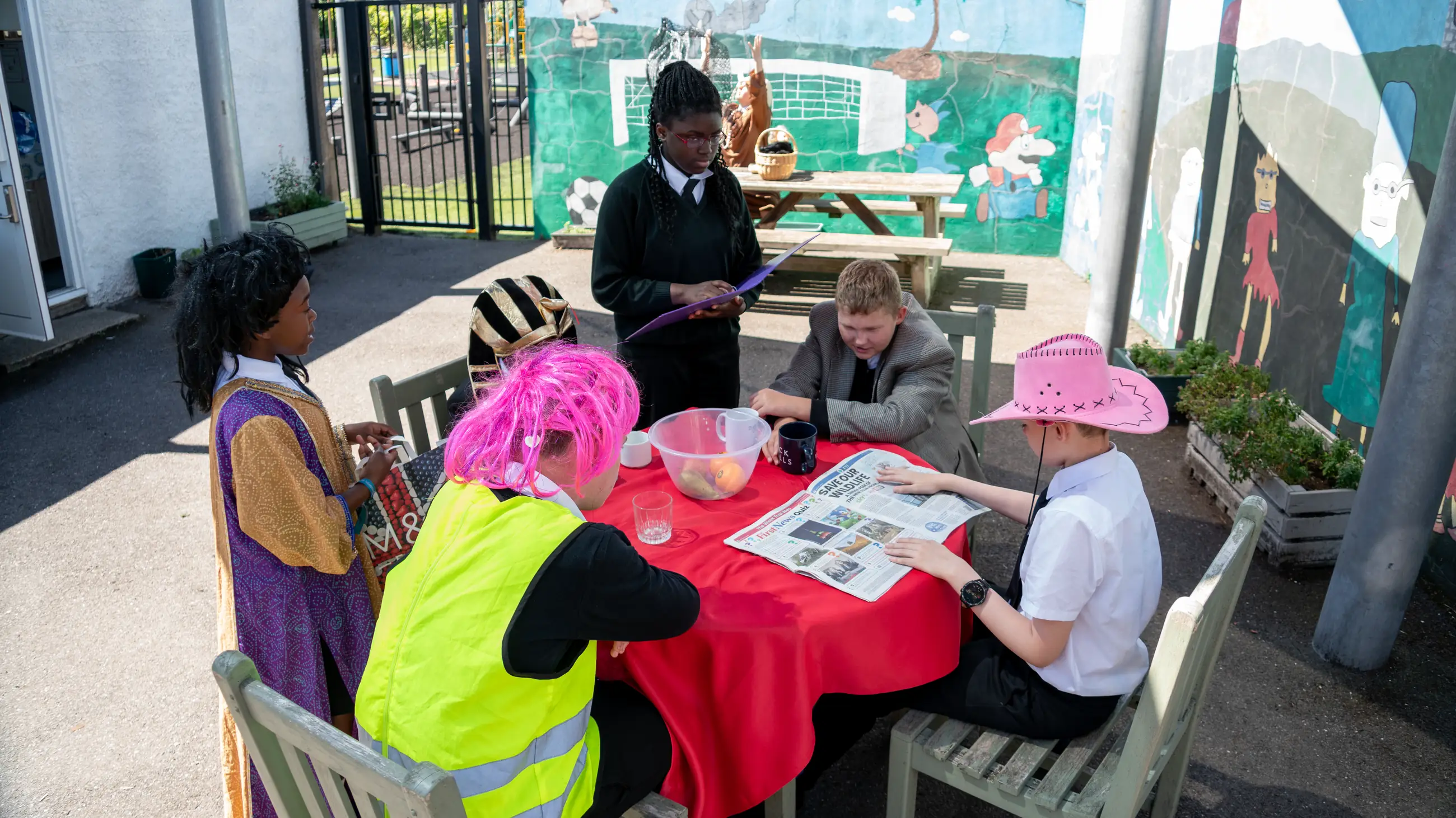 Students and staff seated around a table in the outdoor classroom, working together.