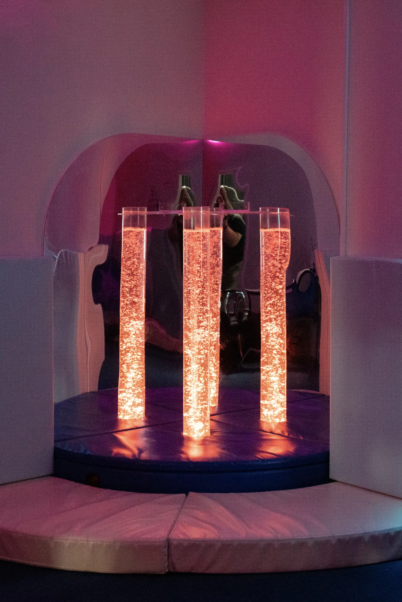 Three illuminated bubble tubes glowing orange in the school's sensory room.